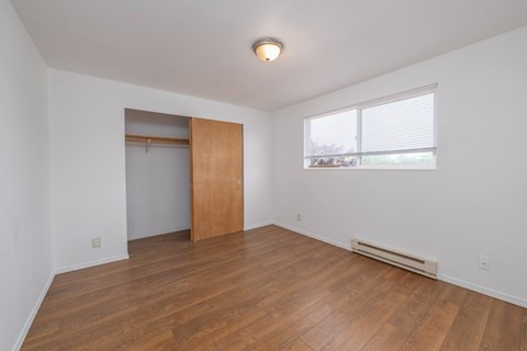 A room with a wooden floor and a window with blinds.