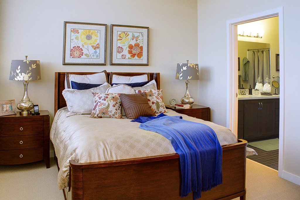 a bedroom with a bed and two nightstands and a bathroom with a mirror