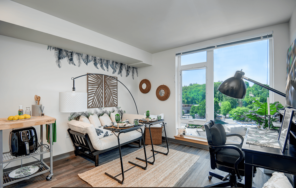 a living room with a couch and a desk and a large window
