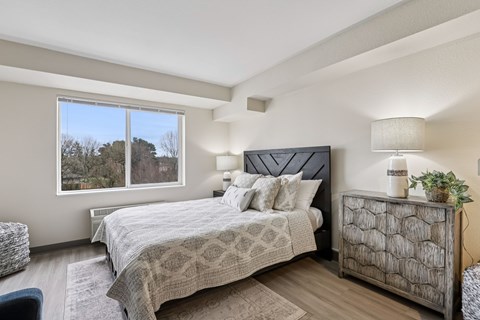 A bedroom with a large bed and a window overlooking trees.