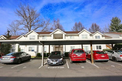 A parking lot with cars parked in front of a white building.