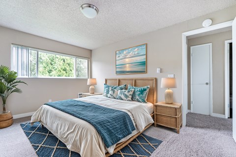 A bedroom with a large bed and a painting on the wall.