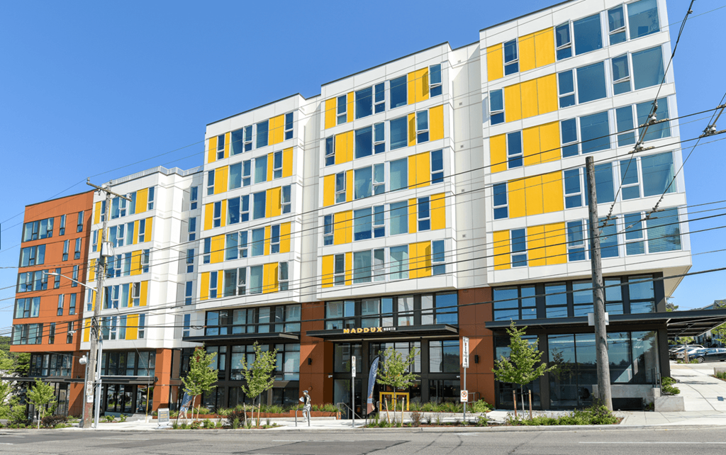 a new apartment building with yellow and orange facade on a city street