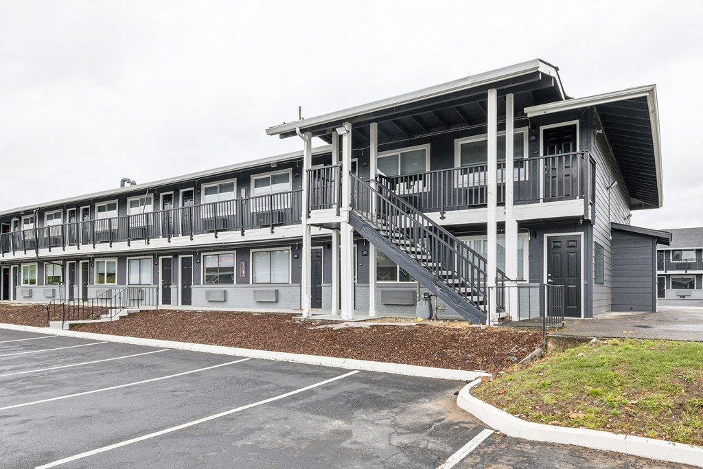 the exterior of an apartment building with stairs and a parking lot