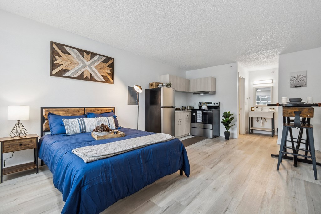 a bedroom with a blue bed and a kitchen with stainless steel appliances