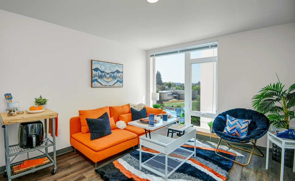 a living room with an orange couch and a large window