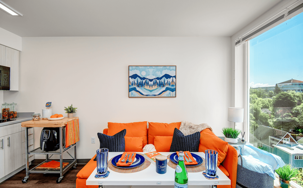a living room with an orange couch and a table and a large window