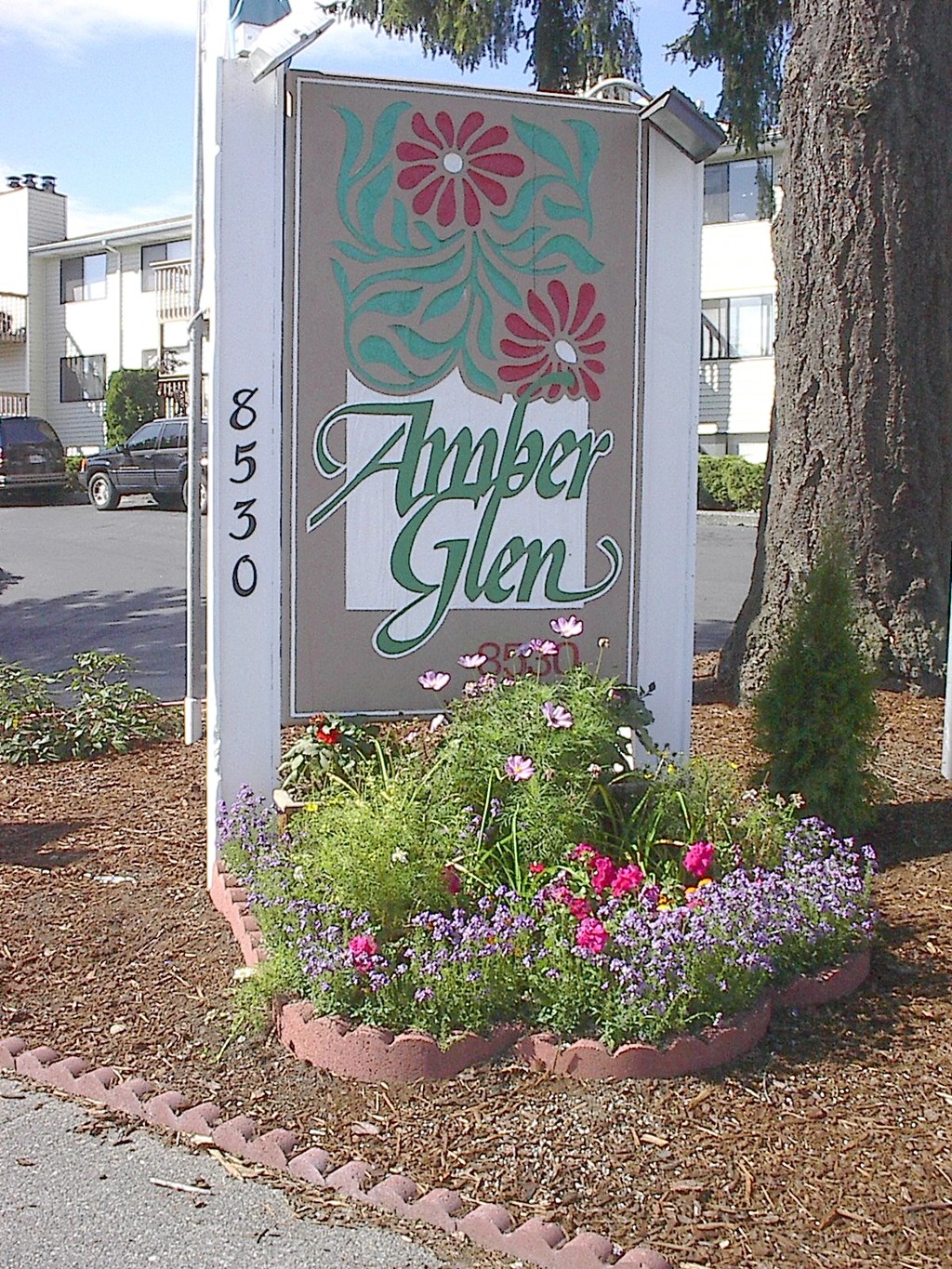 a sign for amoper glen in front of a flower garden