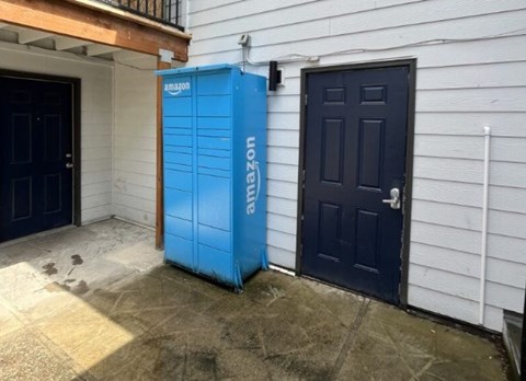 A blue Amazon storage unit sits in front of a house.