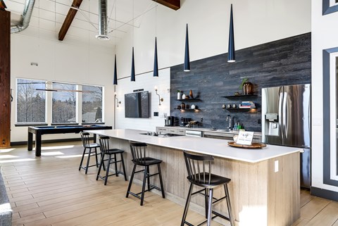 A kitchen with a long white counter and black bar stools.