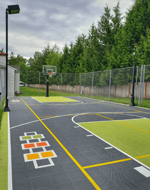 a basketball court in a park with a fence and trees