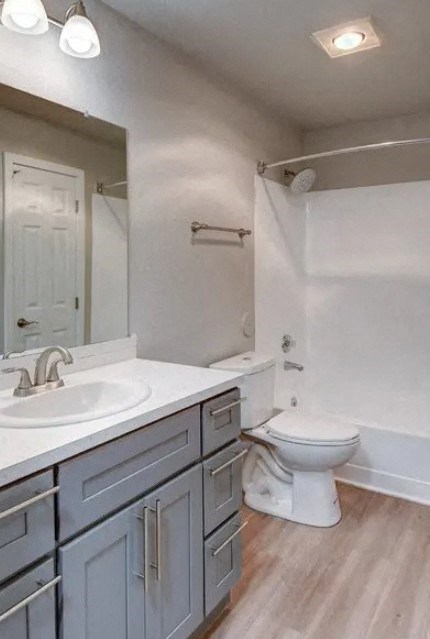 A white toilet is in a bathroom with a white sink and a mirror.