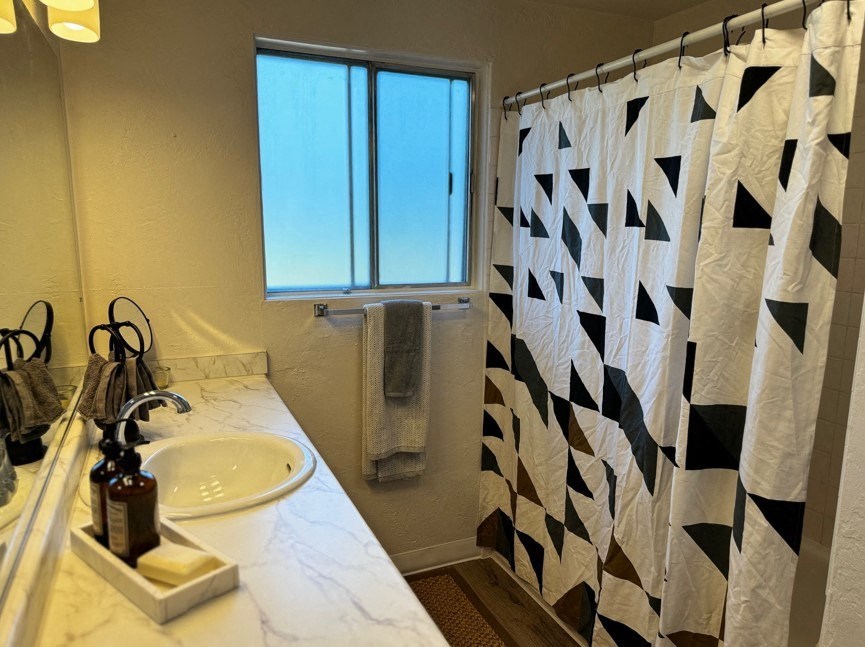 A bathroom with a checkered shower curtain and a marble countertop.