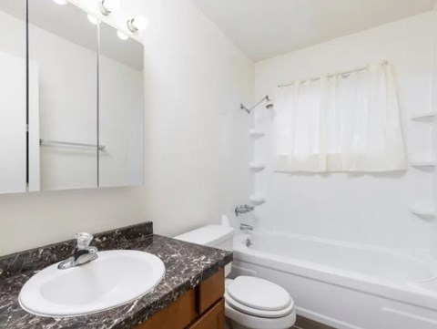 A white bathroom with a marble countertop and a white sink.