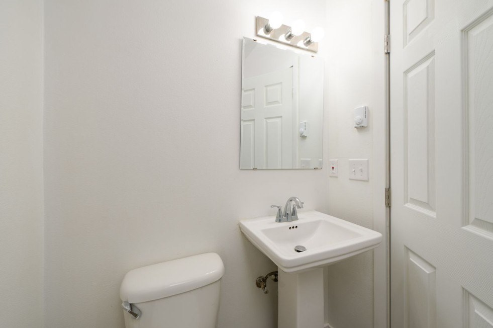 A white toilet sits next to a white sink in a small bathroom.
