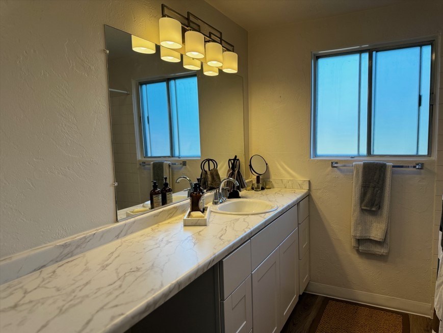 A bathroom with a marble countertop and a large mirror.