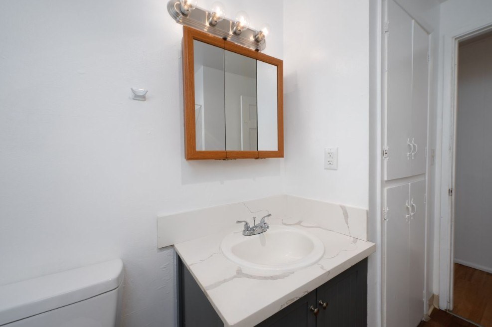 A bathroom with a white sink and a mirror above it.