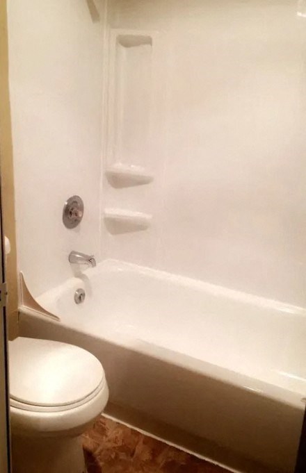 a white bathroom with a toilet and a bath tub