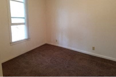 an empty room with a window and a brown carpet
