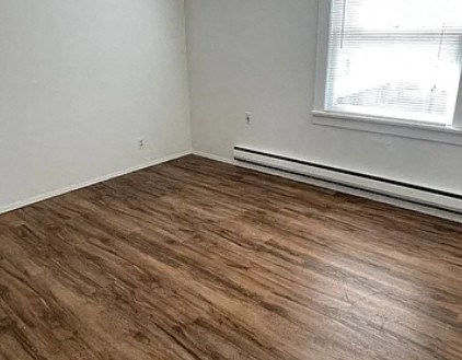 a bedroom with a wooden floor and a window