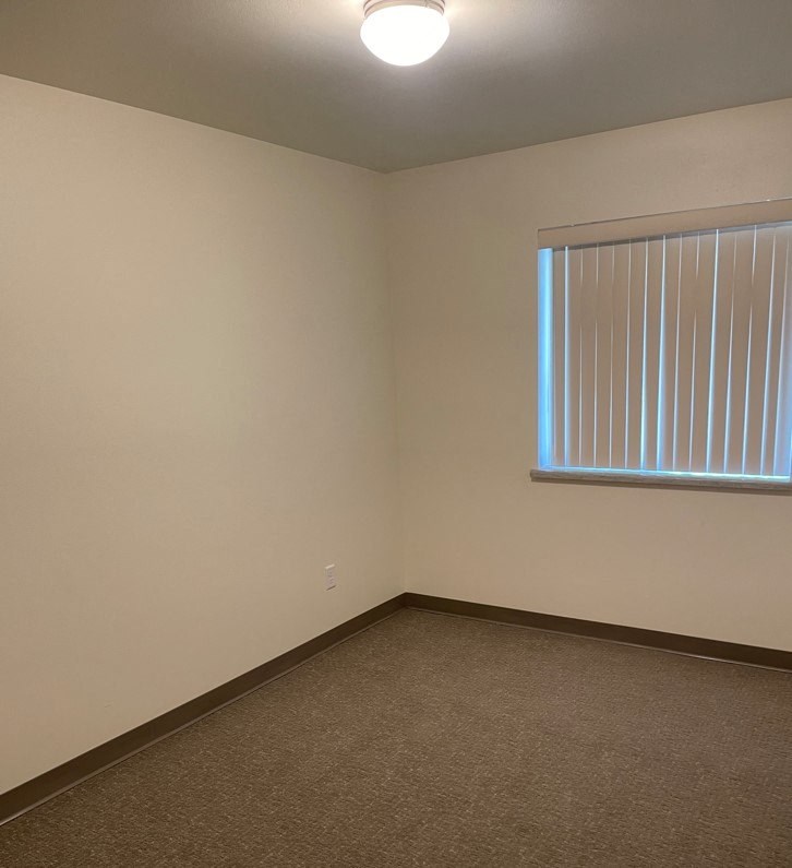 an empty room with a window and a carpet