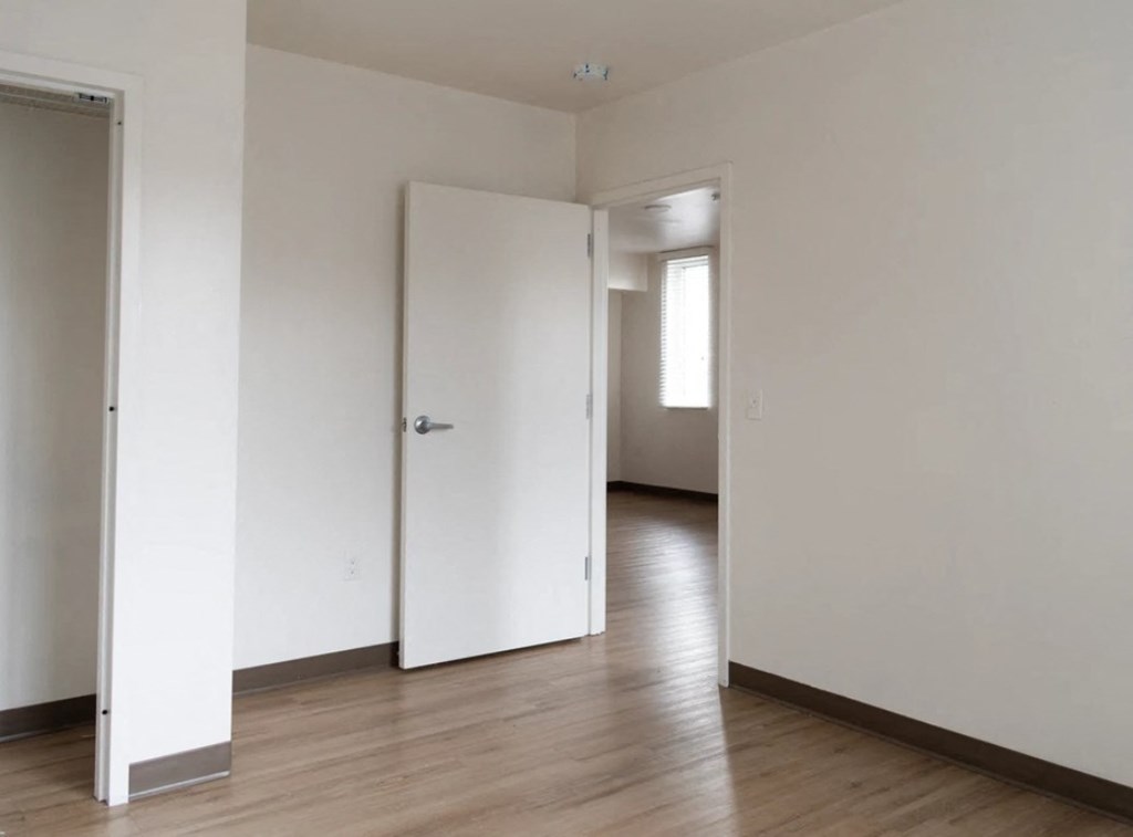 A white door is closed in a room with wooden floors.
