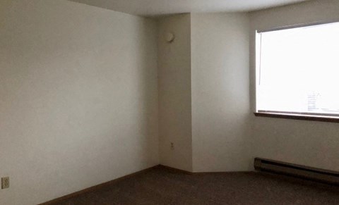 A room with a window and a carpeted floor.