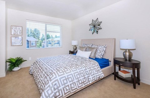 A bedroom with a large bed and a window overlooking a house.