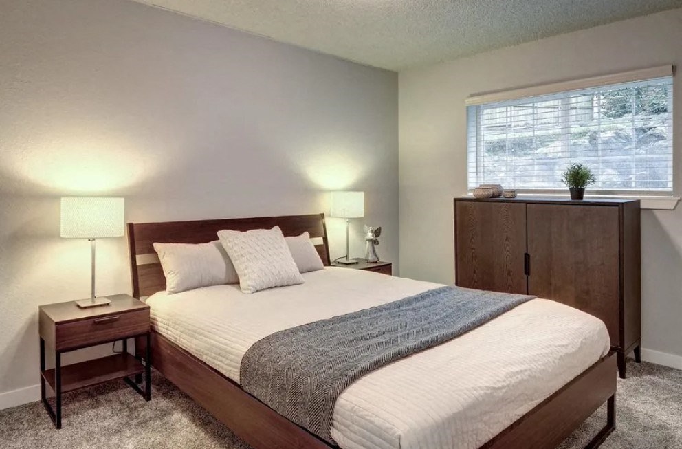 A bedroom with a bed, nightstands, and a window.