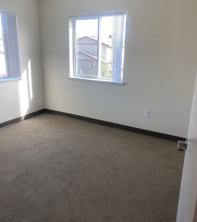 an empty room with a window and a carpeted floor