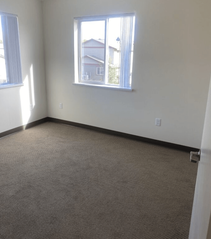 an empty room with a window and a carpeted floor