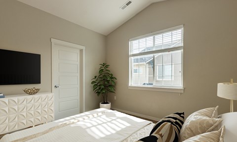 A bedroom with a large bed and a flat screen TV on the wall.