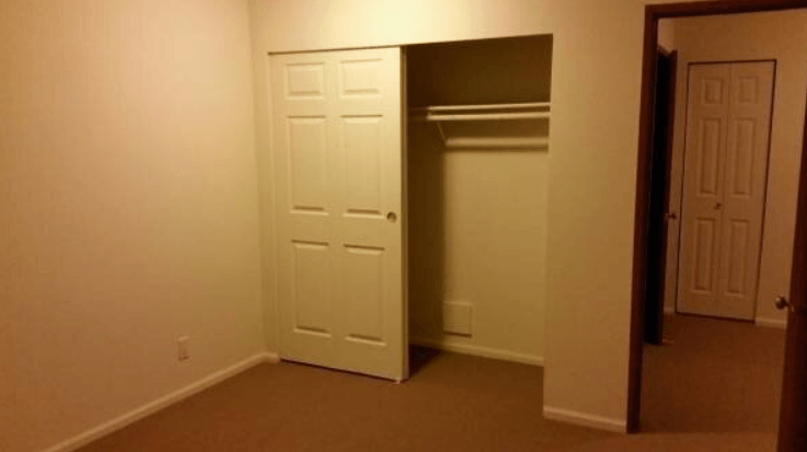 an empty room with a closet and an open door