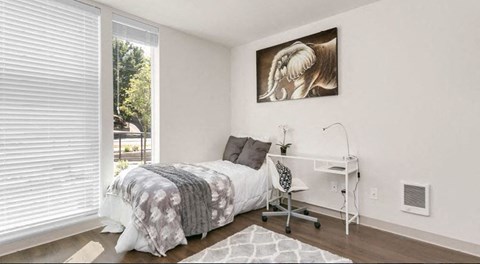 a bedroom with a bed and a desk and a window