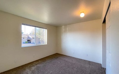 an empty living room with a window and carpet