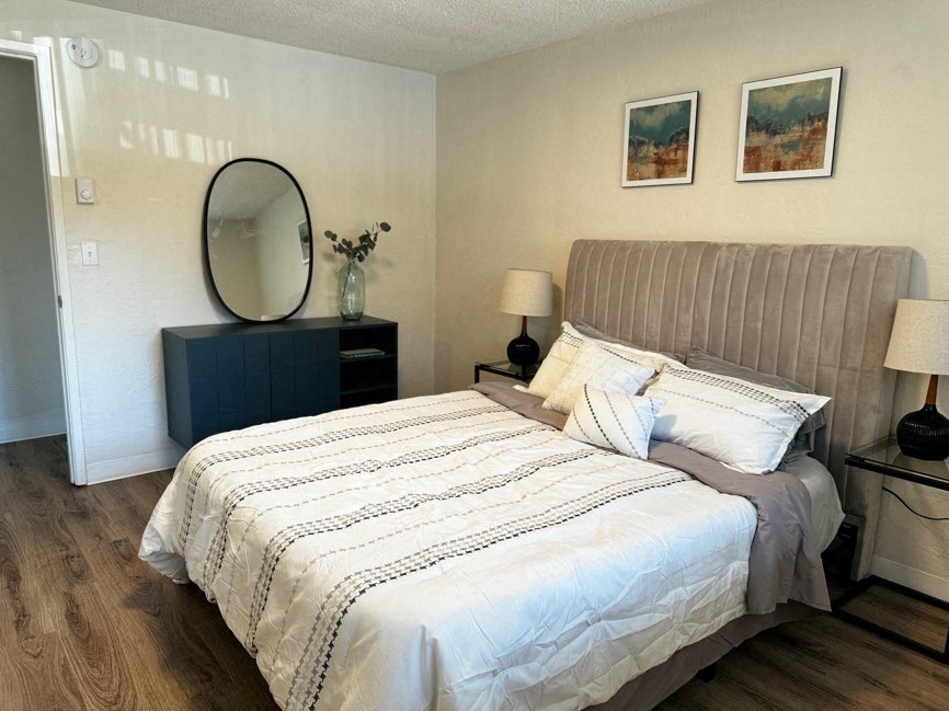 A bedroom with a large bed and a round mirror on a cabinet.