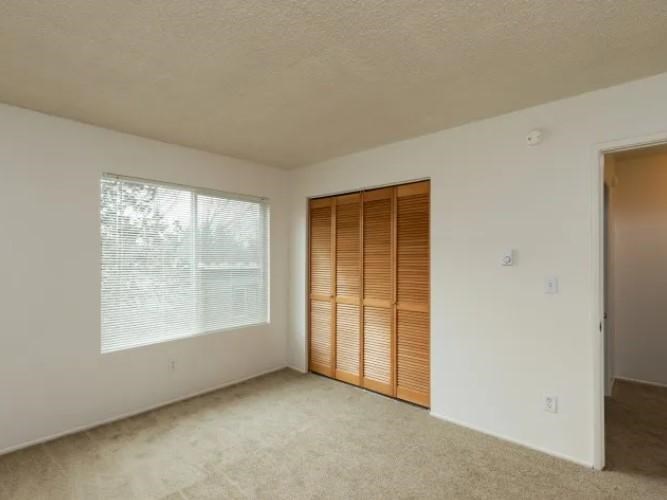 A room with a window covered by wooden blinds and a door.