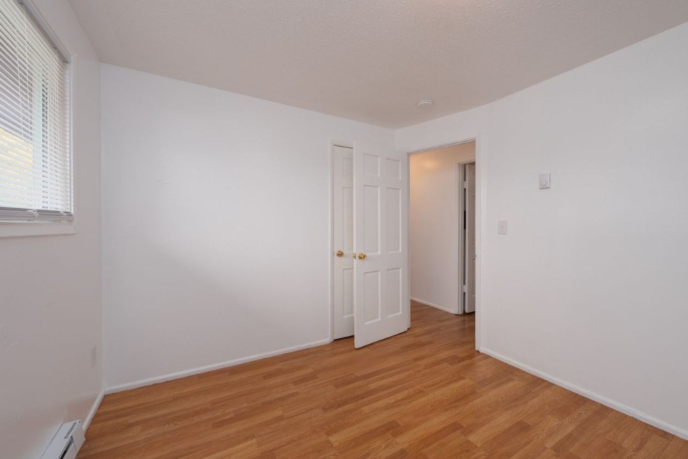 A room with a white door and a wooden floor.