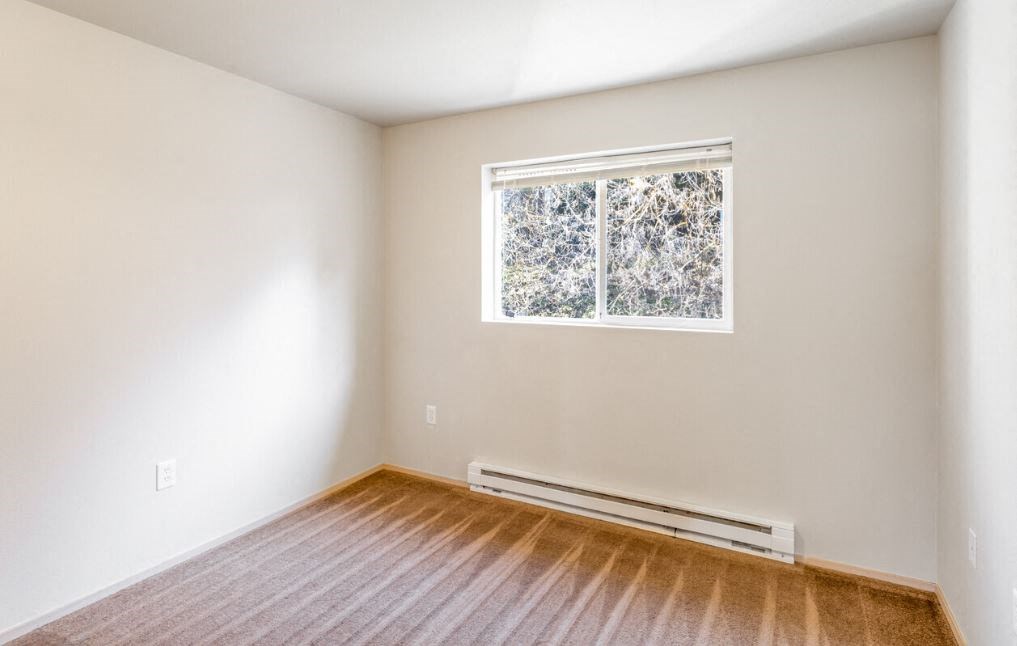 an empty room with wooden floors and a window