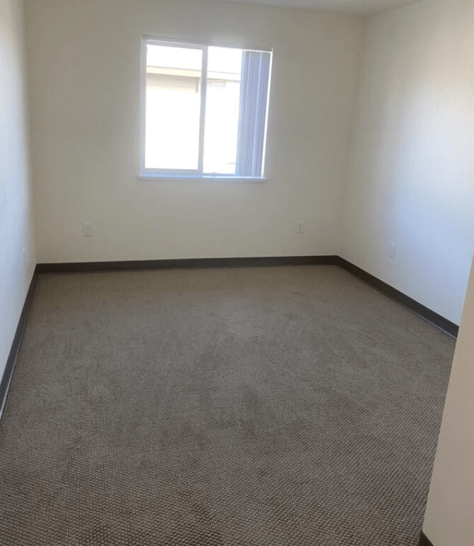 an empty room with a window and carpet