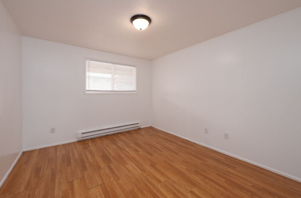 A room with wooden flooring and a window.
