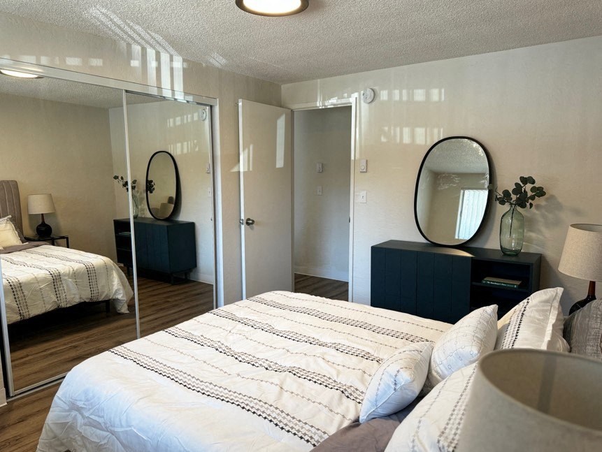 A bedroom with a large bed and a mirrored closet door.