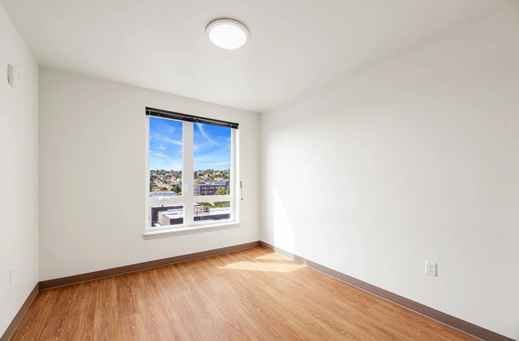 an empty room with a window and wood floors
