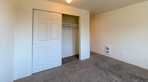 an empty bedroom with a closet and a white door