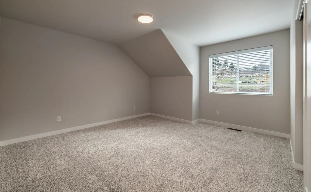 A room with a carpeted floor and a window showing a view of a parking lot.