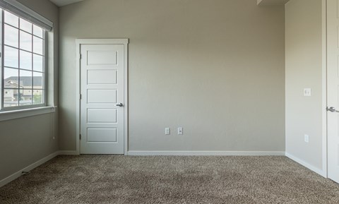 A room with a carpeted floor and a white door.