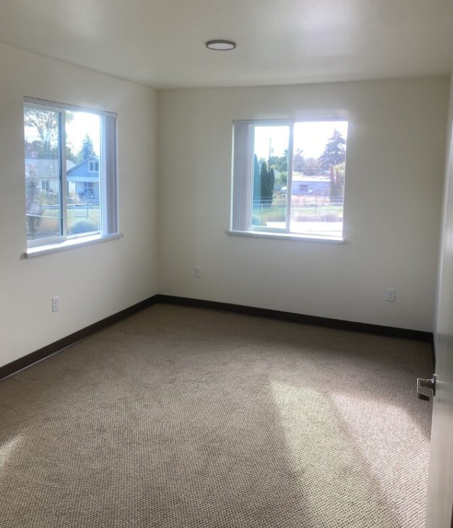 an empty room with two windows in it