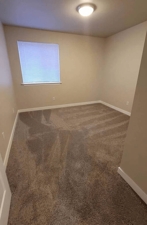 a empty room with a carpeted floor and a window