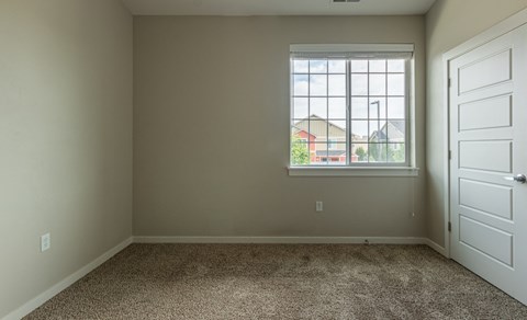 A room with a carpeted floor and a large window.