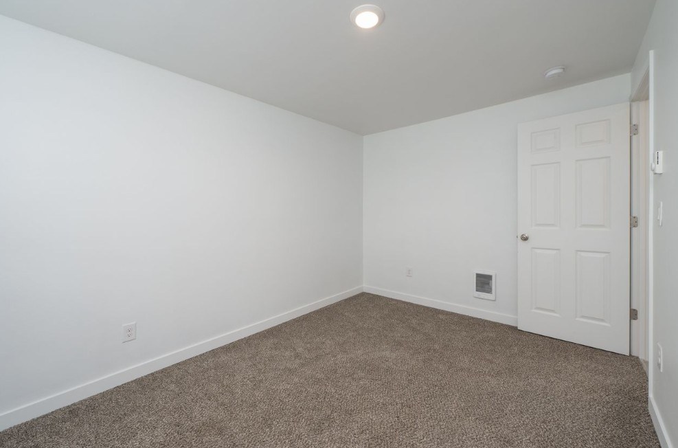 A room with a carpeted floor and a white door.